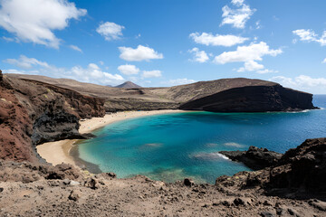 Fototapeta premium secluded island paradise featuring dramatic volcanic mountains behind untouched beach and crystal clear lagoon