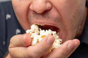 A close-up of a man enjoying popcorn with a focused expression.