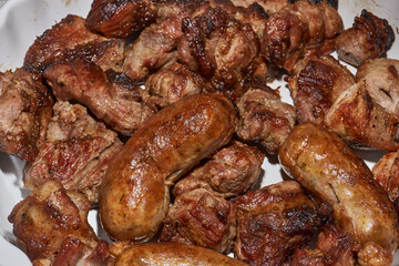 Skewered kebabs and homemade sausages in a white porcelain mold. Close-up.
