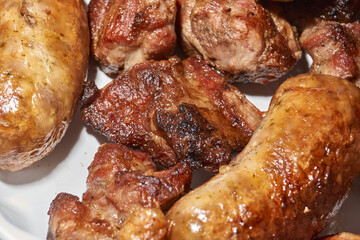 Skewered kebabs and homemade sausages in a white porcelain mold. Close-up.