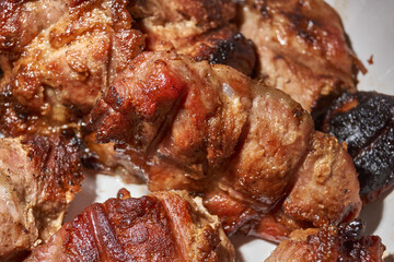 Skewered kebabs and homemade sausages in a white porcelain mold. Close-up.