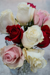 Red, pink, and white roses arranged in a glass vase.