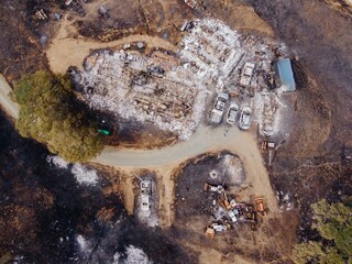 Aerial view of a property destroyed by the LNU Lightning Complex wildfires in 2020 in Napa, California, USA. The remains of a house, vehicles, and equipment are visible amidst the charred landscape.