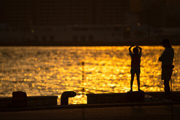 夕日が映える海峡を背にした岸壁の親子20240525