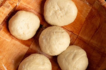 Dough balls rest in a wooden bowl, ready for baking. These simple ingredients are the foundation for delicious homemade bread or dumplings.