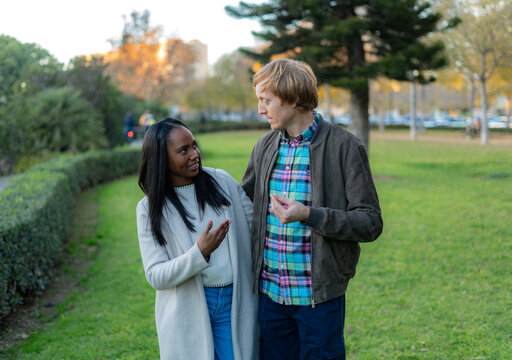 Father and daughter are enjoying a walk in the park, engaging in a lively conversation with expressive hand gestures