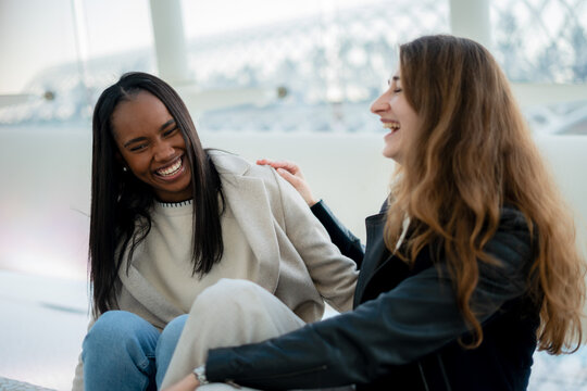Mother and daughter sitting together and laughing, sharing joyful moments in a bright, modern space filled with natural light, creating lasting memories and deepening their bond