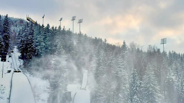 A truly stunning snowy landscape that features an impressive ski jump, surrounded by tall, majestic evergreen trees