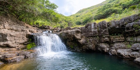 Obraz premium Waterfall cascading into pool, lush green hills