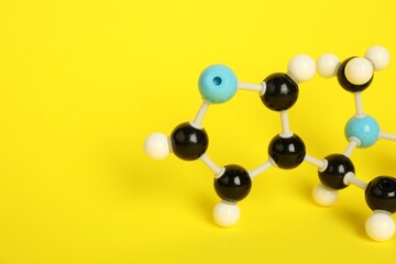 Chemical model of molecule on yellow background, closeup. Space for text