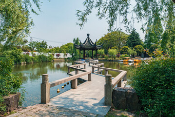 Serene view of a traditional pavilion beside a tranquil lake surrounded by lush greenery