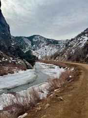 Winter mountain trail with snowy slightly frozen river