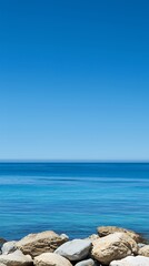 Serene Seascape: Azure Ocean Meeting Clear Blue Sky Over Light Brown Rocks