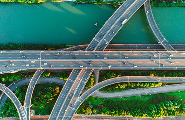 Aerial of vehicles navigate a complex highway system, showcasing overpasses and intersections.