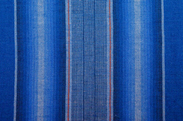The pattern and texture of the blue, black and white cotton striped and checker fabric, a motif that is often used on sarongs in Indonesia.