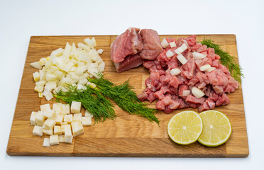 Fresh raw beef with vegetables and ingredients for cooking. Finely chopped meat, celery and onion on a wooden cutting board.