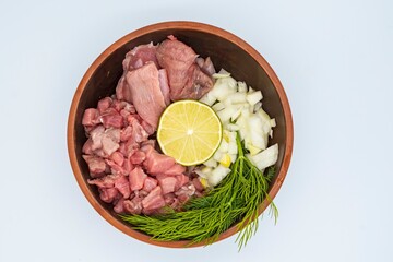 Raw finely chopped beef, onion, celery root, dill and lime in a plate on a white background. Ingredients for Serbian soup chorba.