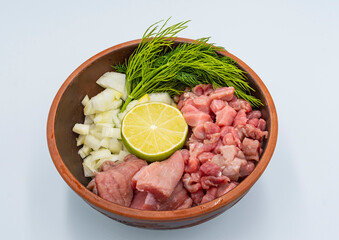 Raw finely chopped beef, onion, celery root, dill and lime in a plate on a white background. Ingredients for Serbian soup chorba.