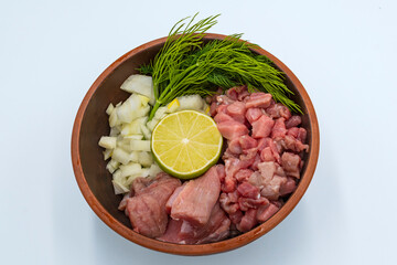 Raw finely chopped beef, onion, celery root, dill and lime in a plate on a white background. Ingredients for Serbian soup chorba.