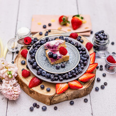 Fresh yoghurt and cake with strawberries and young spring flowers.