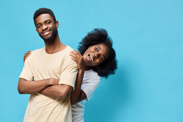 Happy diverse couple posing playfully against a vibrant blue background, showcasing joy and connection, perfect for themes of friendship and love