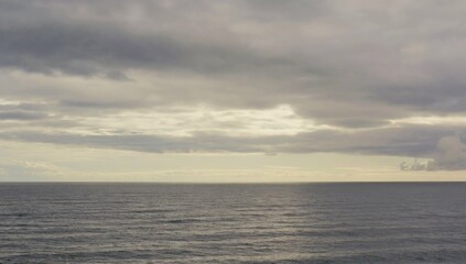 Fototapeta premium Endless Horizon: An expansive view of a serene sea meeting a dramatic, cloud-filled sky, evoking feelings of vastness and contemplation.