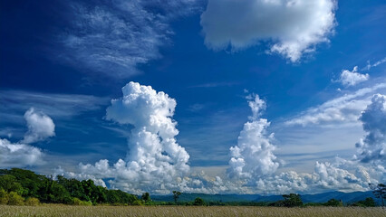 Majestic Cumulus Clouds Against a Deep Blue Sky Over a Scenic Landscape