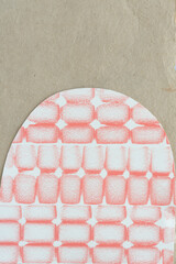 cut paper shape with pastel orange grid pattern on brown paper