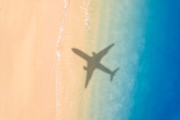 Aerial view of shadow passenger plane silhouette and sandy beach blue sea with waves at sea beach summer vacation sea travel concept	