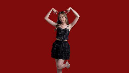 A woman in a black dress is posing for a picture. She is smiling and she is happy