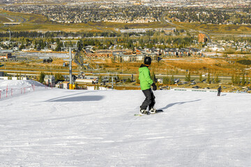 City view from the top of the ski hill with a snowboarder riding downhill