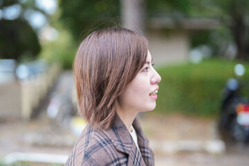 Winter at Ohori Park in Chuo Ward, Fukuoka City, Japan. A 29-year-old Japanese woman wearing a checkered coat. She walks with a smile.