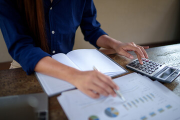 Businesswoman calculating company budget using a calculator and documents at a natural-themed...