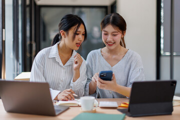 Obraz premium Two happy business asian women coworking with a laptop in a desktop at office 