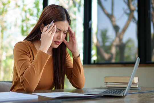 Businesswoman analyzing documents with a stressed expression in a natural-themed office, dealing with work challenges.