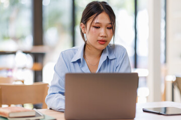 Young asian female entrepreneur working on a laptop at business meeting in a corporate workplace.
