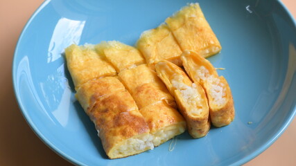 roll omelette stuffed with chesse and rice on blue plate, delicious food in the morning