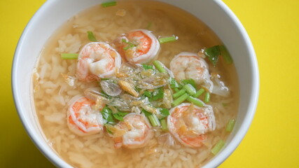 rice soup with shrimp in white bowl on yellow background