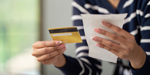 Woman holding credit card and bills, assessing her financial situation.