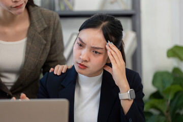 Stressed professional woman receiving support from a colleague during a meeting.