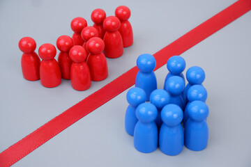 Groups of blue and red people figures separated by red line on gray background. 