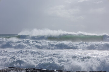 Heavy surf and rough seas with wind spray and moody grey skies just prior to a hurricane or tropical cyclone edge reaching  Snapper Rocks in Coolangatta on the Gold Coast in Queensland, Australia.
