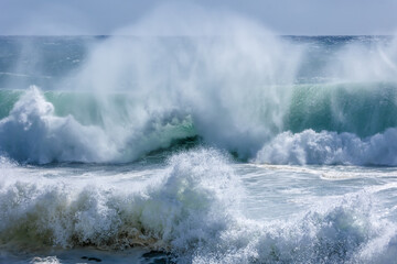 Massive waves crashing with wind spray flying and surf boiling as the edge of a cyclone or hurricane pushes large surf onto Snapper Rocks in Coolangatta on the Gold Coast in Queensland, Australia.