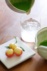 fresh matcha tea, green tea pouring on a glass of coconut water and colorful peach fruit shape Plating balls, Thailand style dessert on wooden table.