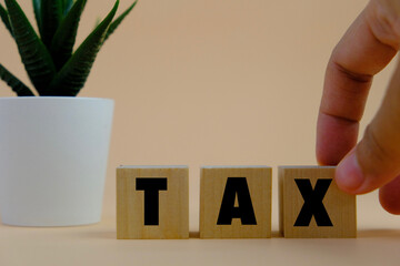 Close-up Of Person Hand Using Calculator With Tax Word On Wooden Blocks.