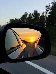 car rear view side mirror at sunset on the road