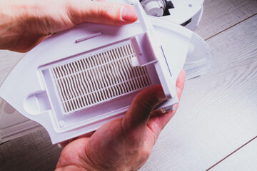 Maintenance of the robot vacuum cleaner. Replacement of brushes and filter. The master repairs the vacuum cleaner. Gloves and a master's tool.