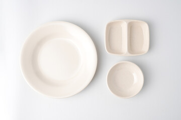 Empty beige colored round shaped plate and dual dipping bowl. Isolated on white background. Flat Lay Setup