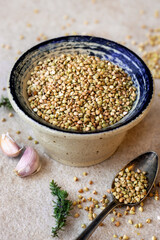 Hulled Buckwheat grains in a rustic bowl against light stone background