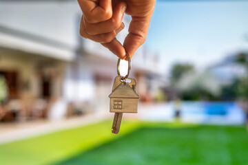 Real estate agent holding house keys while showcasing a new property in the background, symbolizing...